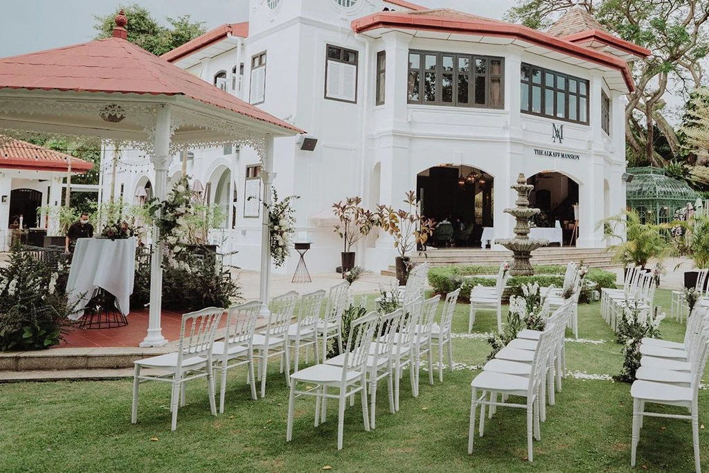 White garden chairs arranged on lawn for wedding at The Alkaff Mansion heritage venue.
