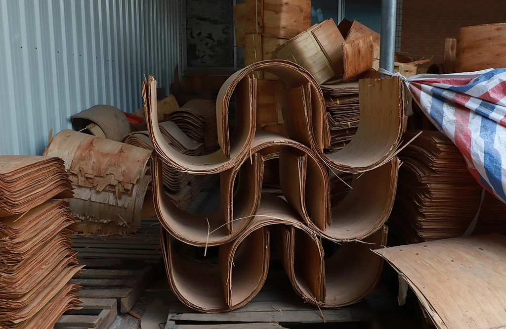 Stacks of curved wood veneers and plywood ready for chair manufacturing.