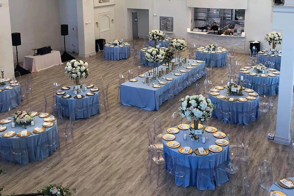 Clear acrylic ghost chairs arranged in grand ballroom with blue table linens.
