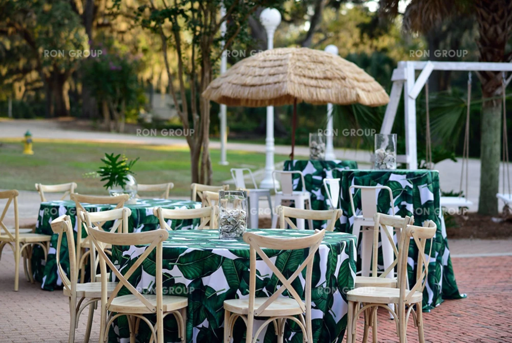 Outdoor setup with custom tropical leaf tablecloths and cross back chairs