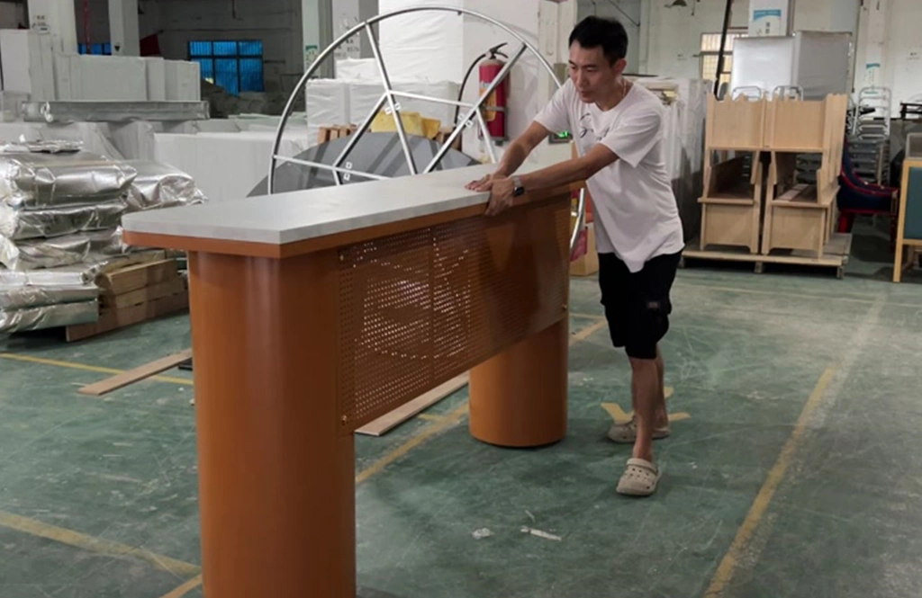 Worker inspecting the surface and stability of a large orange bar counter.