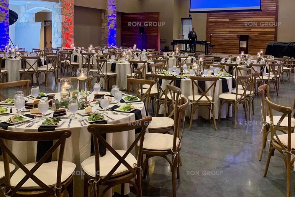 Large rustic reception hall filled with wooden cross back chairs