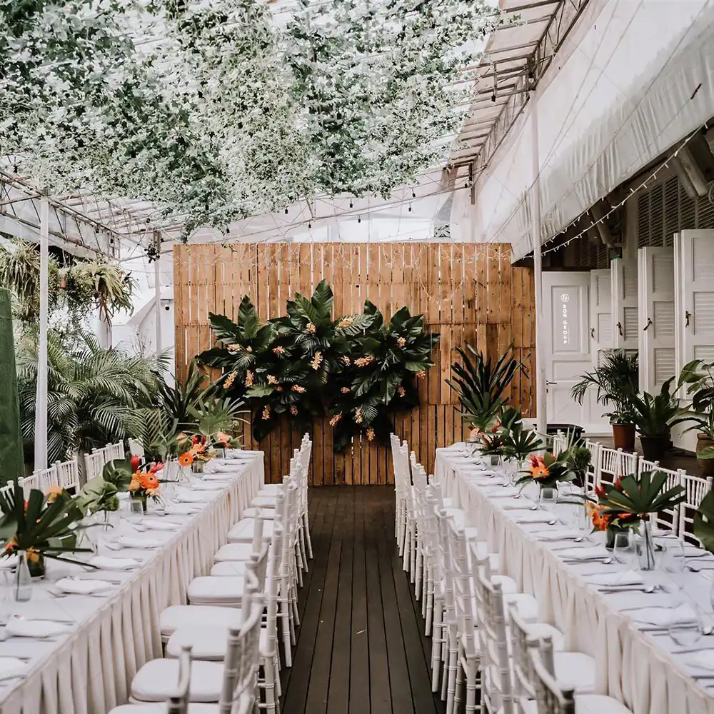 Elegant long table wedding dining setup in a greenhouse conservatory setting