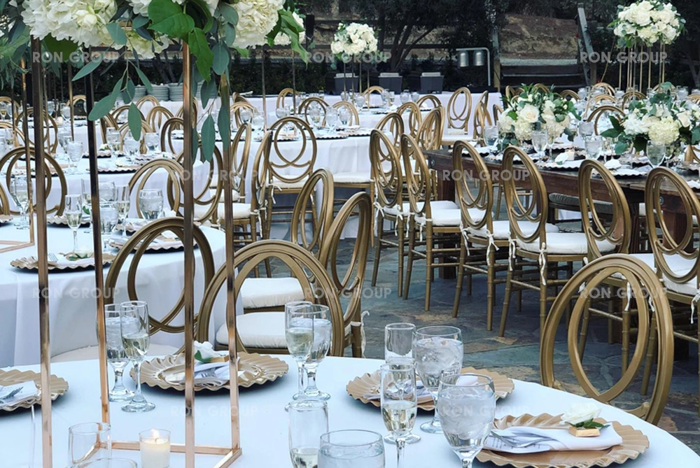 Gold stainless steel O-back chairs in a garden wedding setting