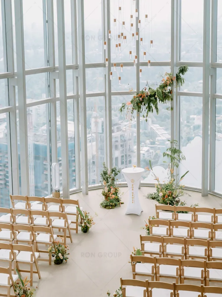 Wooden folding chairs for bright indoor wedding ceremony with city view
