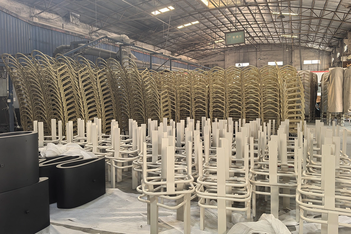 Large quantity of metal chair frames stacked in the factory warehouse.