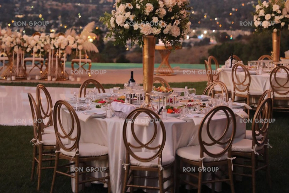 Outdoor sunset wedding featuring gold infinity chairs and elegant dining