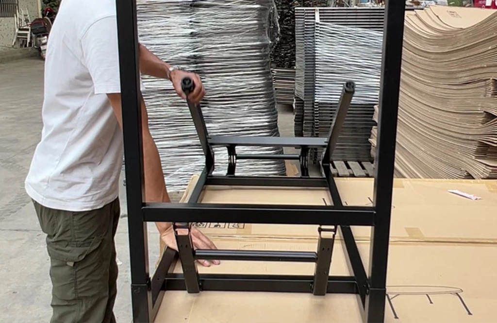 Worker testing the folding mechanism of a black table leg frame.