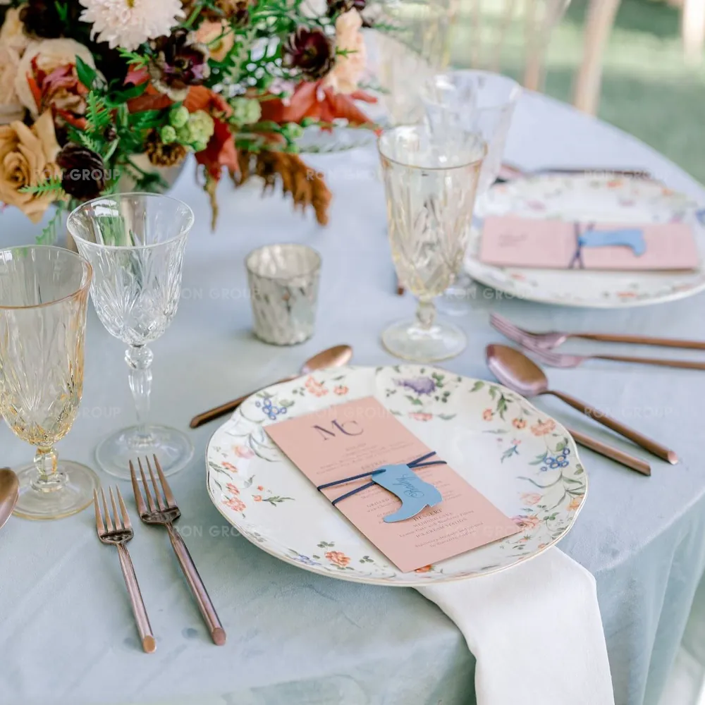 Close up of vintage amber goblets and floral china plate on blue tablecloth